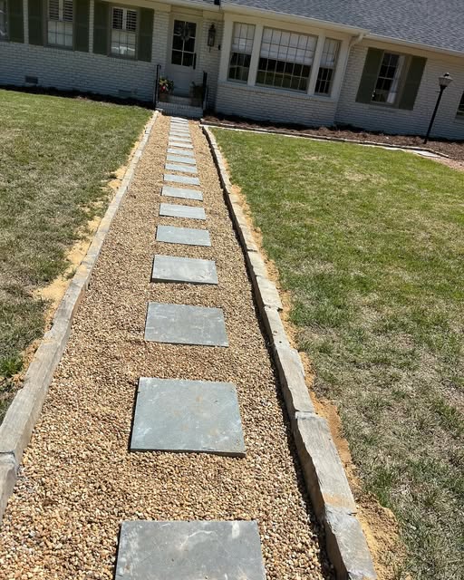 Straight gravel walkway with square stepping stones leading to a front door