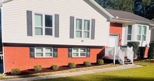 Fresh red mulch and trimmed shrubs across the front of a home