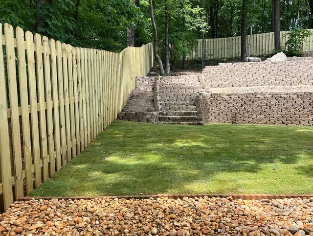 Finished terraced retaining walls, stairs, lawn, and wooden privacy fence